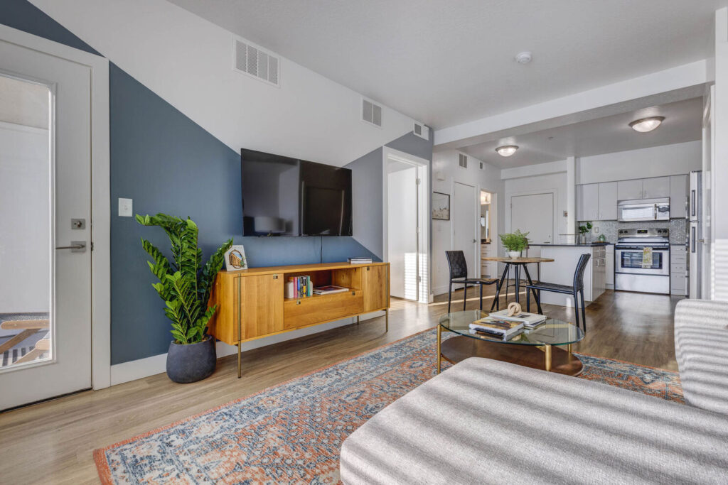 view of living room with the kitchen, dining area and glass door- grey decor