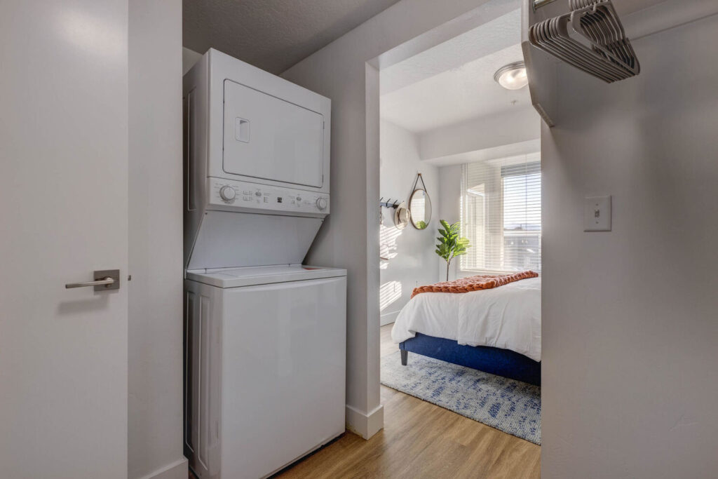 Walk in closet in the bedroom with a stackable washer and dryer