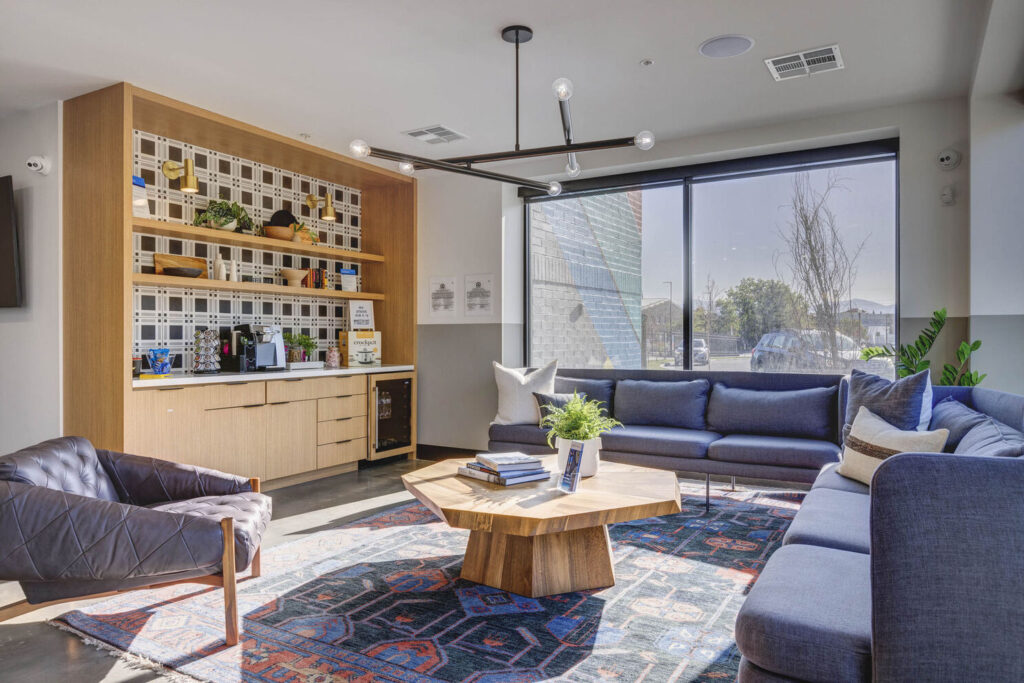 sitting area in the clubhouse with small refrigerator area with brown counter and shelves for food prep or additional decor