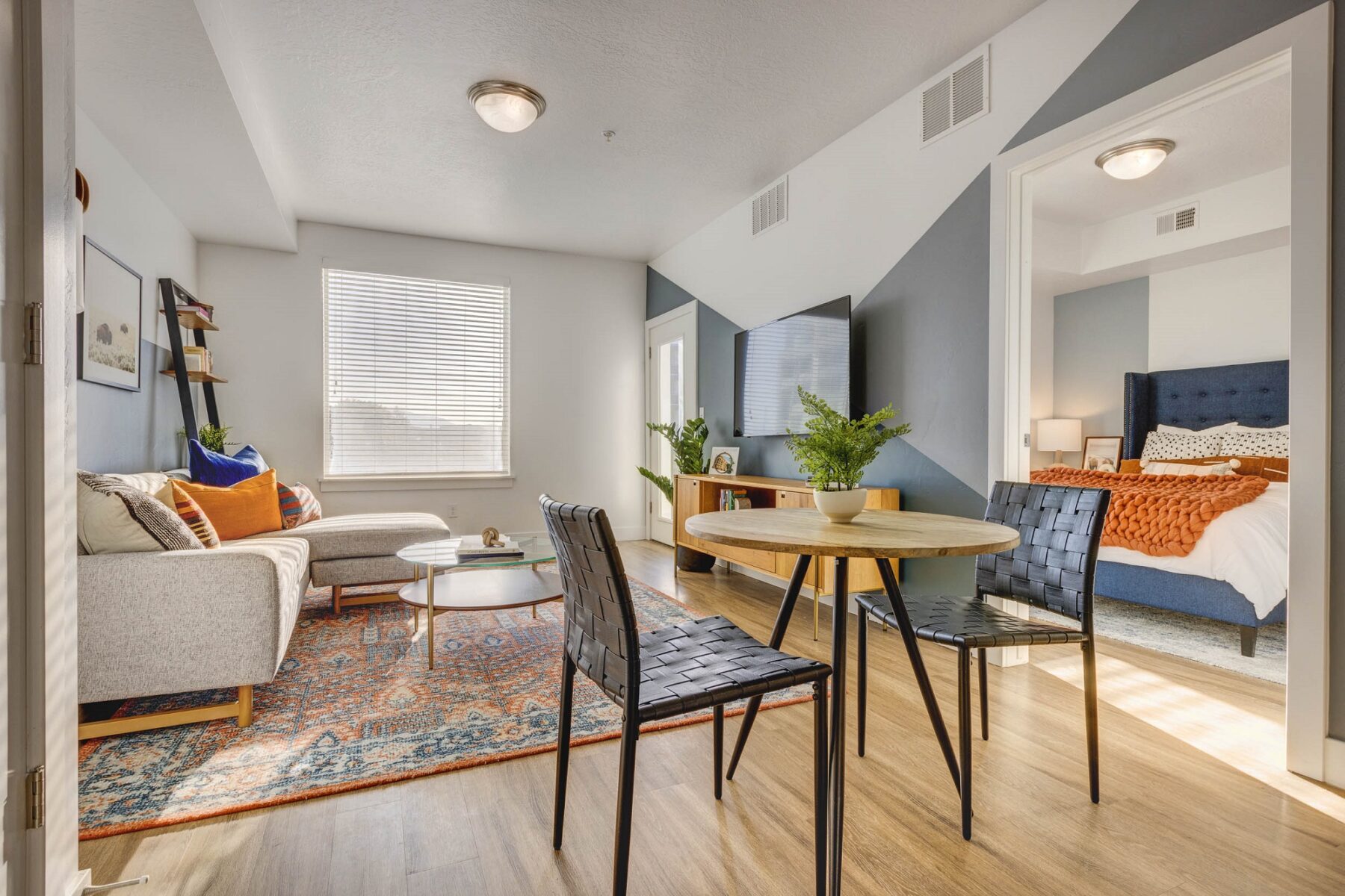 living room view with the small dinning area that hold one circle table and two chairs and a view of bedroom entrance