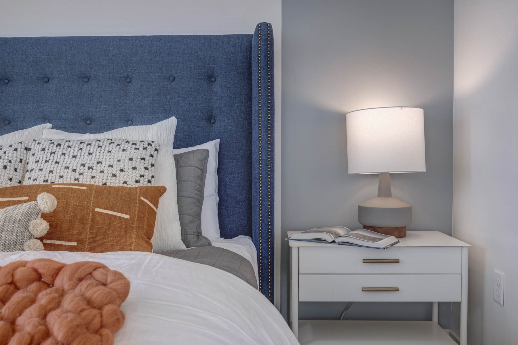 blue headboard on a bed with a white small bedside table with drawers