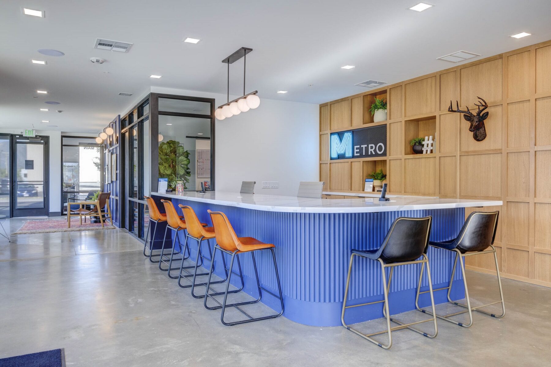 The serving counter in the clubhouse at featuring comfortable grey cushioned chairs and natural light shining through glass doors and windows