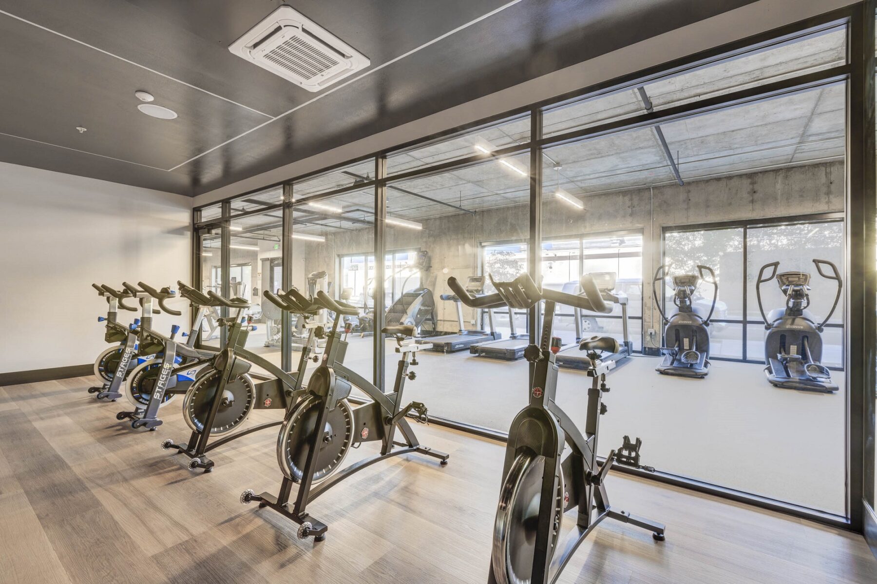 indoor gym stationary bikes, a glass wall that separates those from the stair masters