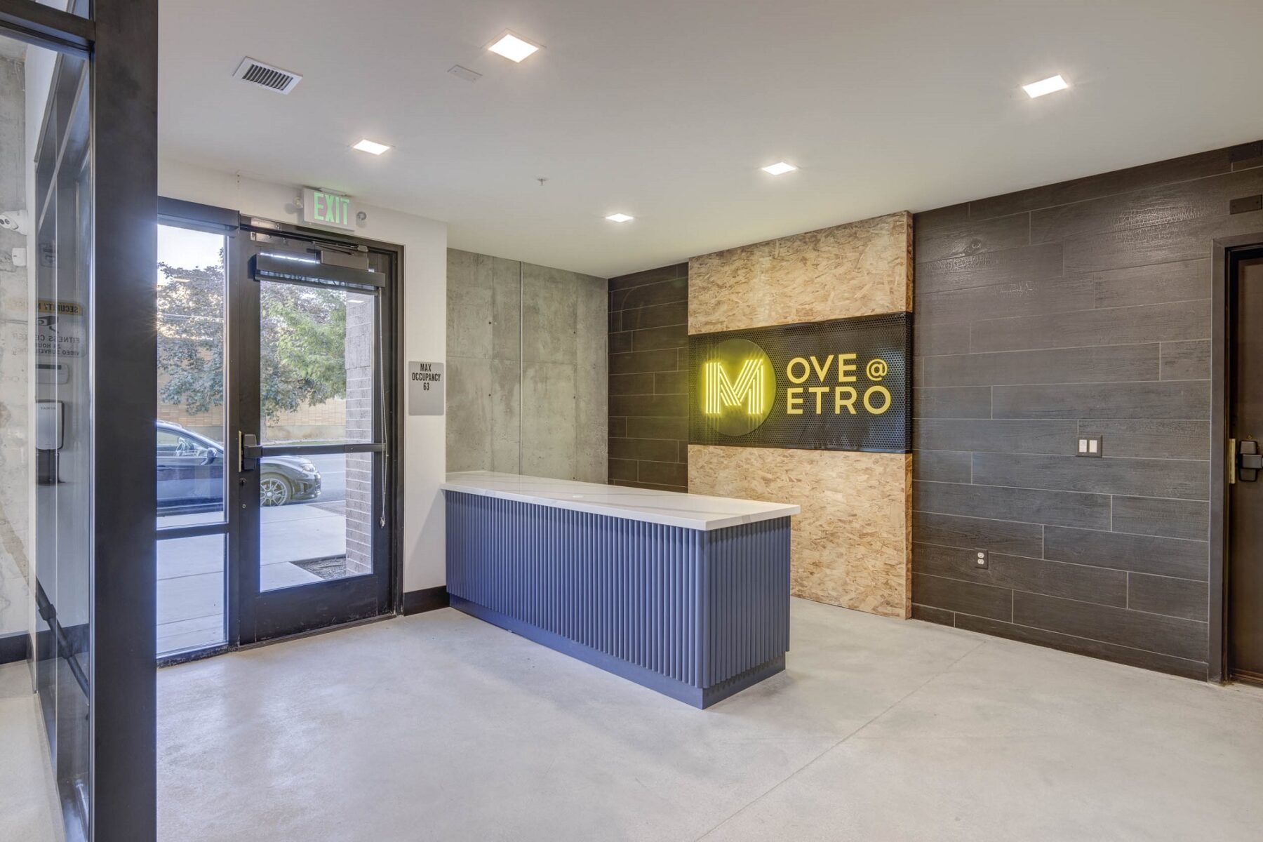 Entrance to clubhouse with Metro Logo Light up sign in yellow on back wall, island countertop in front of sign