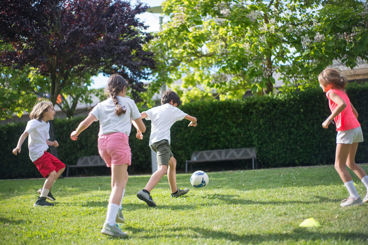 Children playing soccer in a green grass field